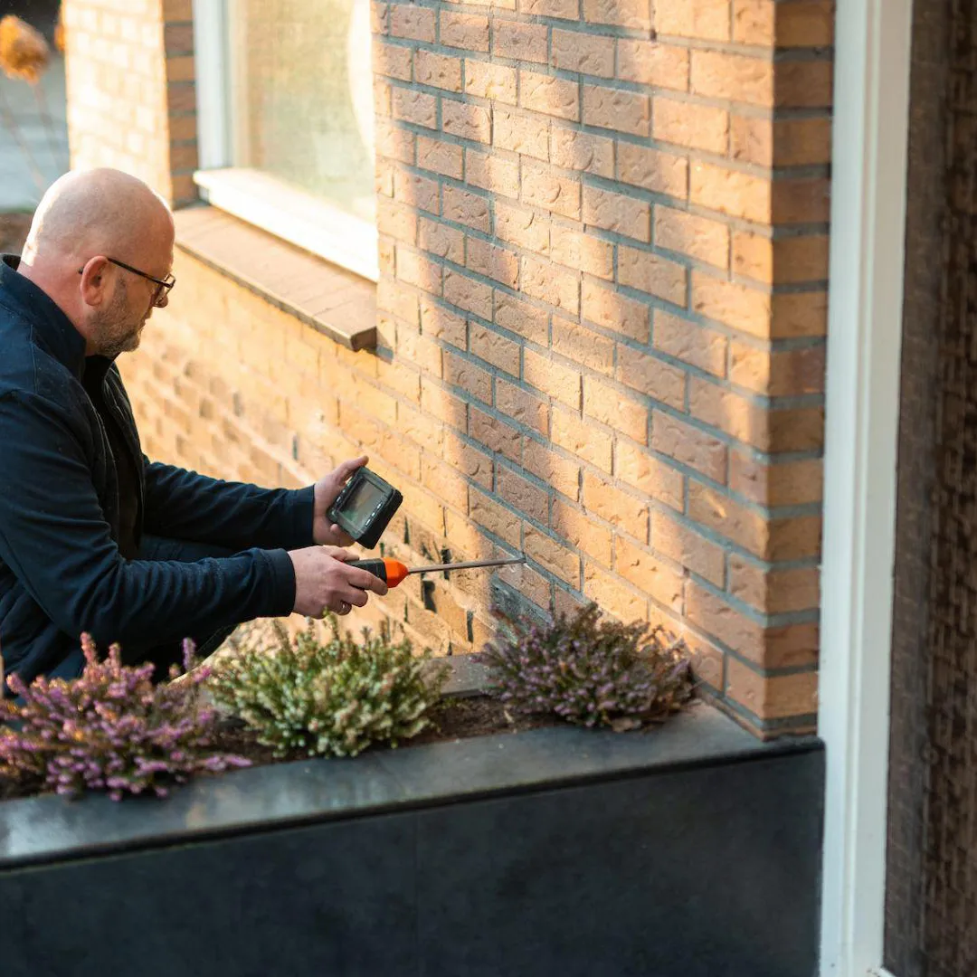Specialist van iSO22 inspecteert de spouwmuur van een woning